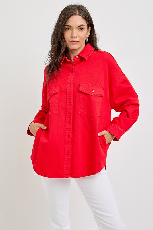 Model in a bold red button-down denim shacket with chest pockets, styled effortlessly with white pants.