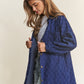 Woman wearing J.NNA rhombus stitched button-up denim shacket, showcasing its stylish oversized fit and unique stitching.