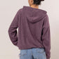 Cozy purple brushed hoodie with kangaroo pocket, perfect for casual days and lounging, styled with denim shorts.