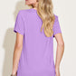 Woman wearing a Bamboo V-Neck High-Low T-Shirt in purple, back view, showcasing slightly stretchy material and basic style.