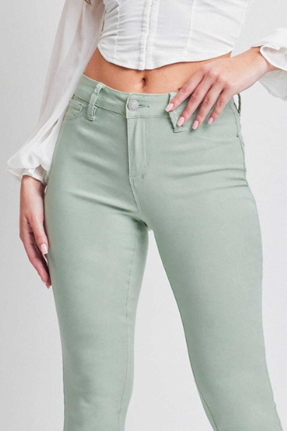 Woman wearing mint green Hyperstretch Mid-Rise Skinny Jeans by YMI Jeans, showcasing a flattering and comfortable fit.