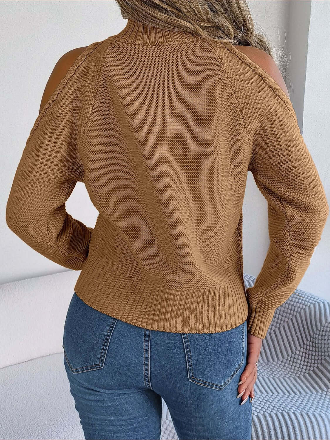 Woman wearing Bella Road Cable-Knit Cold Shoulder Turtleneck Sweater in tan, paired with jeans, trendy and cozy style.