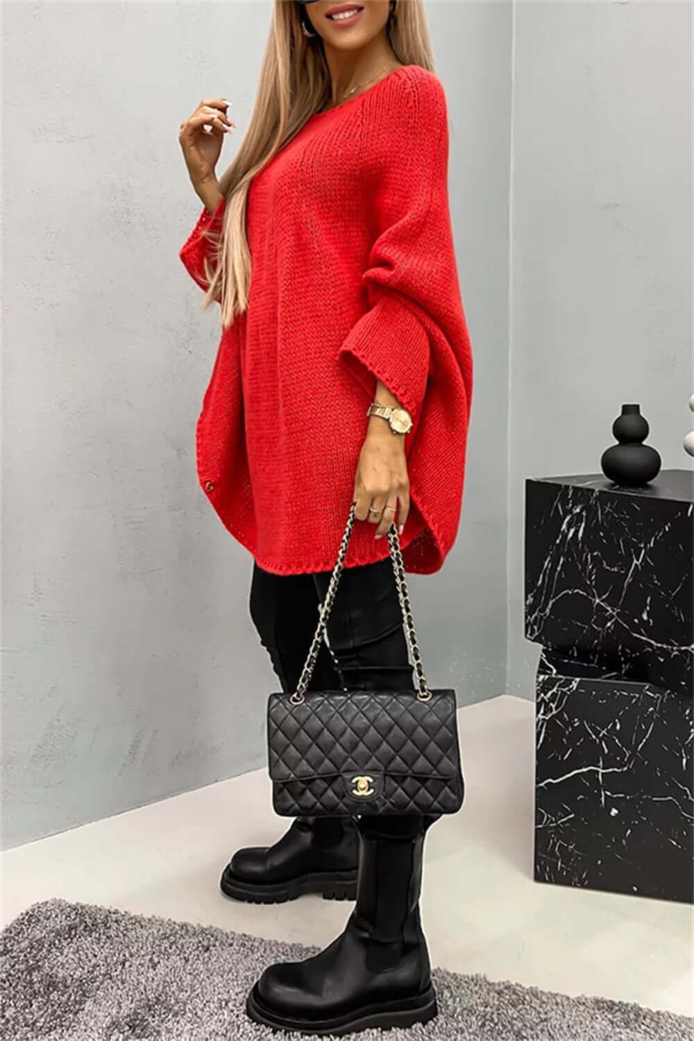 Woman wearing red Bella Road batwing sleeve sweater with quilted purse and boots.