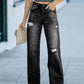 Woman wearing Distressed Straight Leg Jeans paired with a grey crop top and holding a beige clutch.