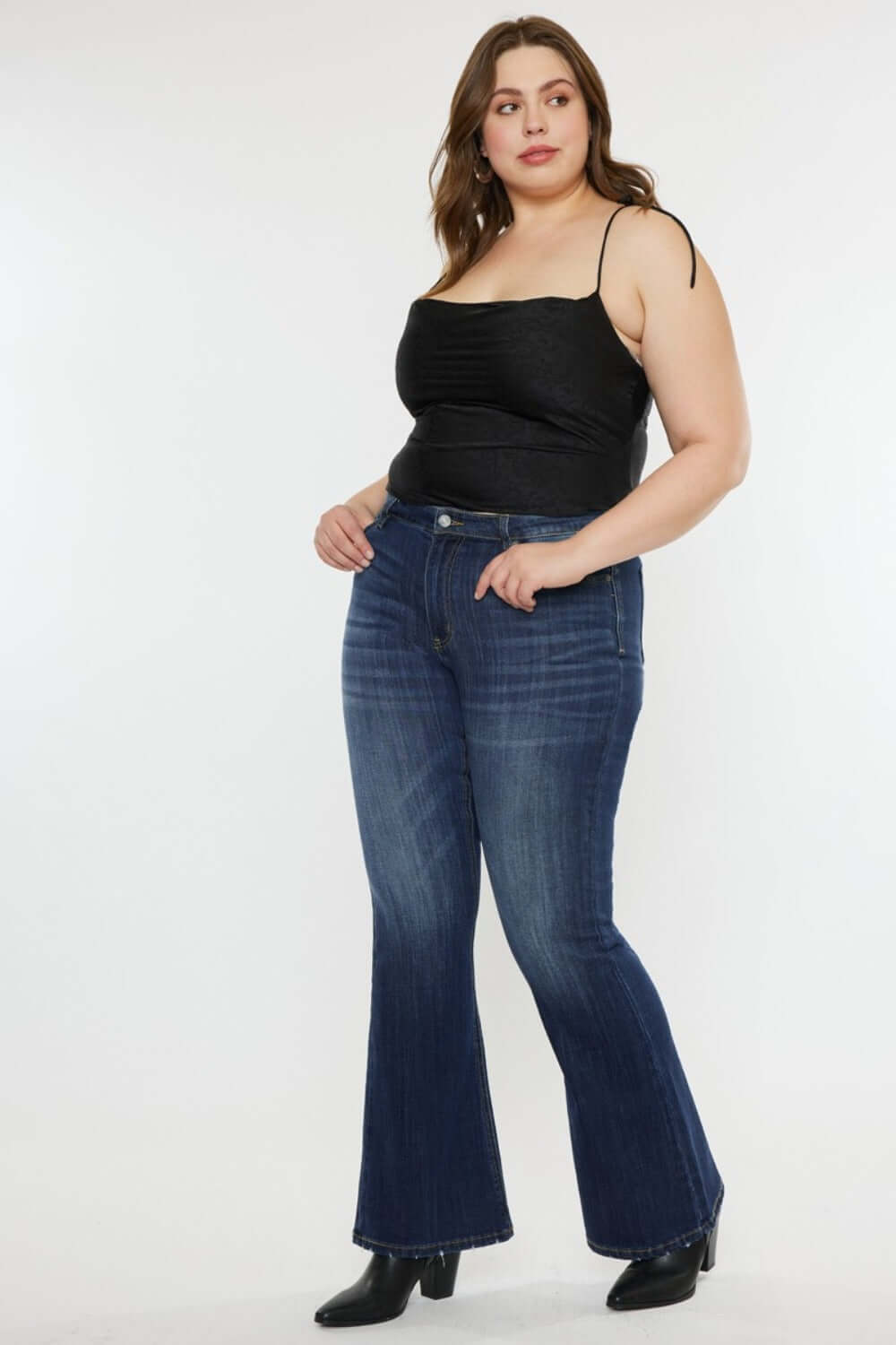 Woman modeling Kancan Full Size Mid Rise Slim Flare Jeans in dark stone wash, showing a chic and versatile denim style.