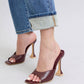 Stylish burgundy open-toe heels paired with rolled-up denim jeans for a chic, modern look.