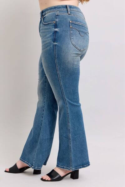 Model showcasing Judy Blue Mid Rise Tummy Control Vintage Wash Jeans with stylish black heels.