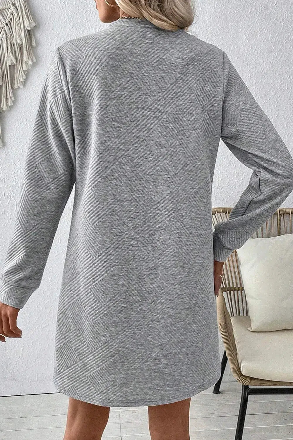 Woman wearing a Bella Road textured gray long sleeve mini dress, showcasing a relaxed fit and stylish pattern.