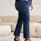 Woman wearing RFM Jeans Tummy Control Distressed High Waist Raw Hem Jeans with black heels in stylish indoor setting.