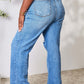 Woman wearing high waist distressed Judy Blue jeans in full size with back view to highlight the flattering fit and contemporary style.