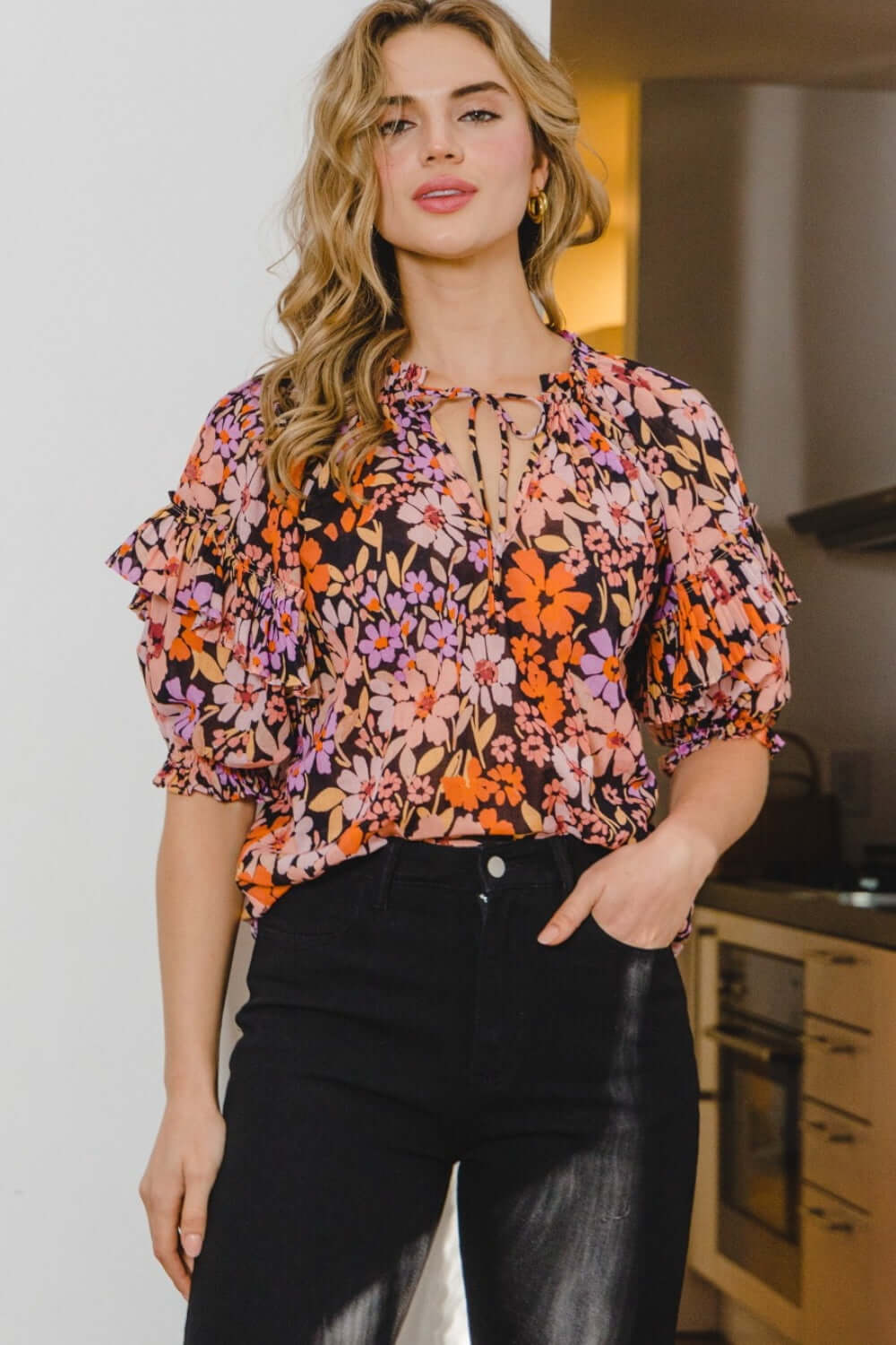 Woman wearing floral tie neck ruffled blouse with charming print and elegant details.