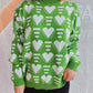 Woman wearing Bella Road Heart Contrast Long Sleeve Dropped Shoulder Sweater in green with white hearts paired with black pants.