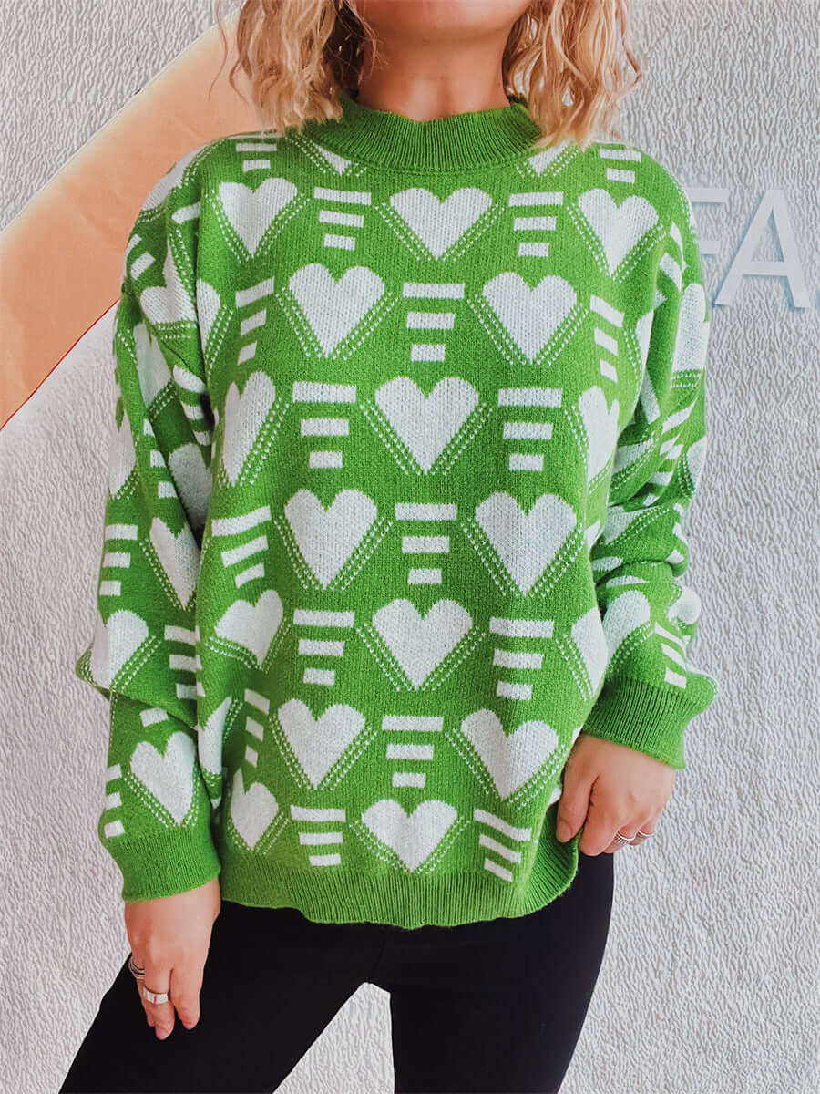 Woman wearing Bella Road Heart Contrast Long Sleeve Dropped Shoulder Sweater in green with white hearts paired with black pants.