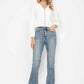 Model showcasing white button-up top with bootcut jeans, stylish and trendy denim outfit.