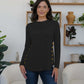 Woman wearing FAM-FAM Round Neck Long Sleeve T-Shirt with decorative buttons, perfect for casual style, in a cozy living room setting.