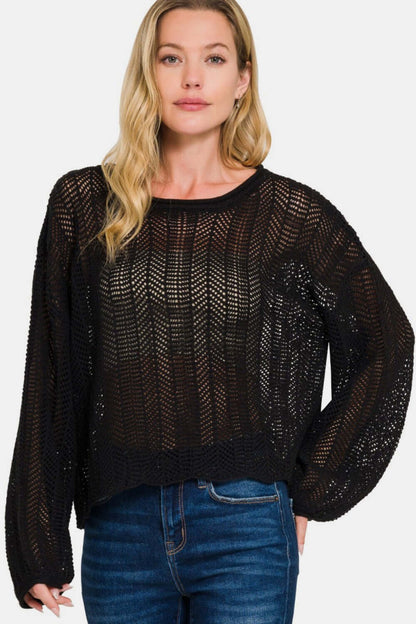 Zenana hollow out long sleeve knit cover up in black, showcasing intricate eyelet design and trendy fashion layered over jeans.