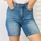 Woman wearing Judy Blue Jeans Tummy Control Double Button Bermuda Denim Shorts, showcasing comfortable and stylish high-quality denim shorts.