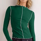 Model wearing a green mock neck long sleeve T-shirt with white contrast trim, styled casually.