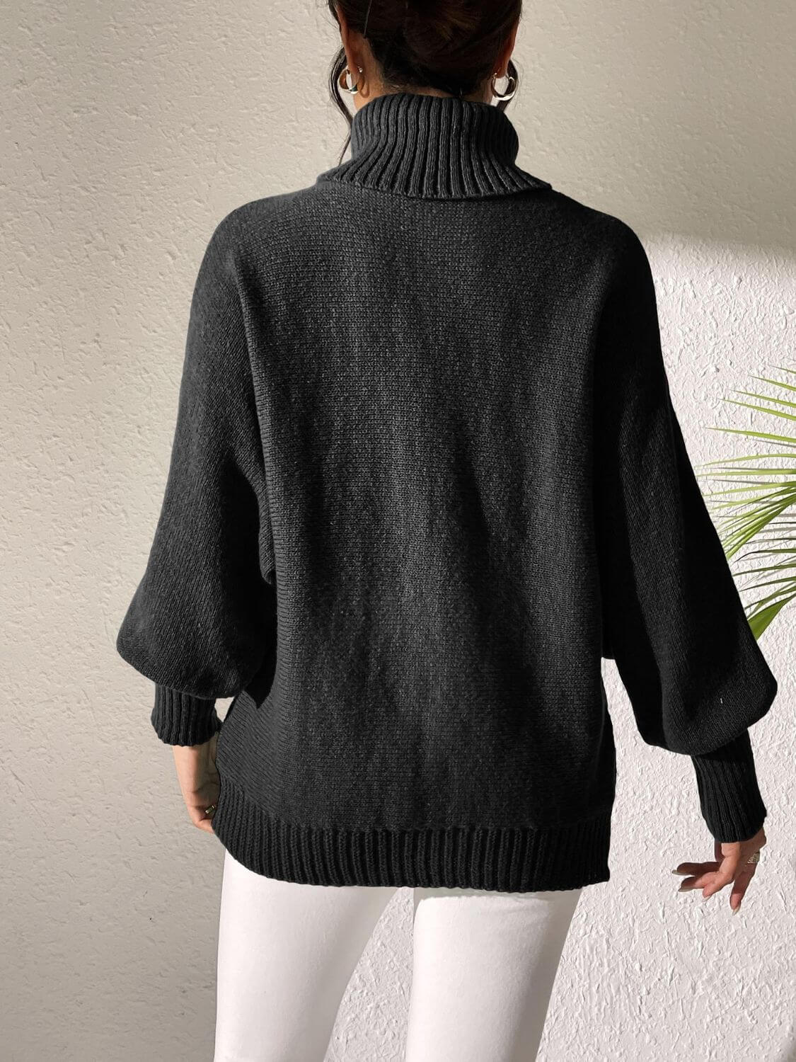 Woman wearing Bella Road Lip Turtleneck Long Sleeve Sweater in black, showcasing its stylish and playful design from the back view.