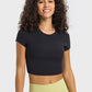 Stylish woman in a black cropped sports t-shirt paired with light green yoga pants, perfect for workouts and yoga sessions.