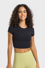 Stylish woman in a black cropped sports t-shirt paired with light green yoga pants, perfect for workouts and yoga sessions.