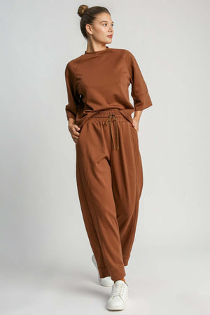 Model showcasing Umgee full size drawstring wide leg pants with pockets in warm brown, styled for comfort and elegance.