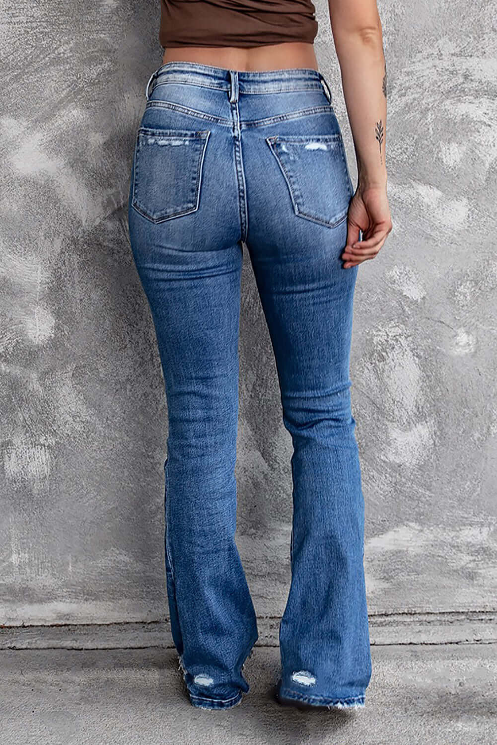 Back view of Bella Road Sequin Bow Distressed Bootcut Jeans showing slightly stretchy denim with distressed detailing on the pockets.