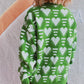 Woman wearing green Bella Road Heart Contrast Long Sleeve Dropped Shoulder Sweater with white heart patterns, back view