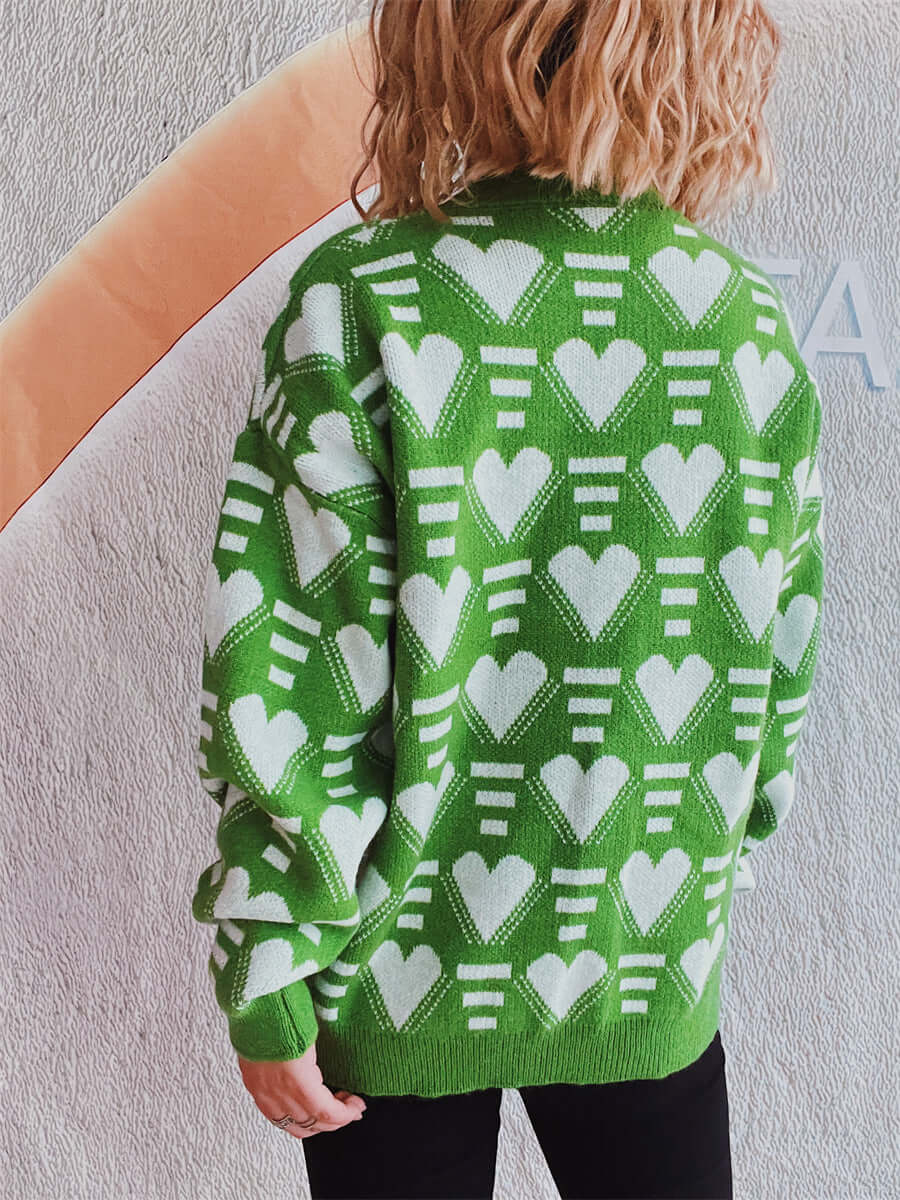 Woman wearing green Bella Road Heart Contrast Long Sleeve Dropped Shoulder Sweater with white heart patterns, back view