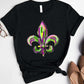 Bella Road Mardi Gras graphic tee featuring vibrant purple and green fleur-de-lis design on a black background.