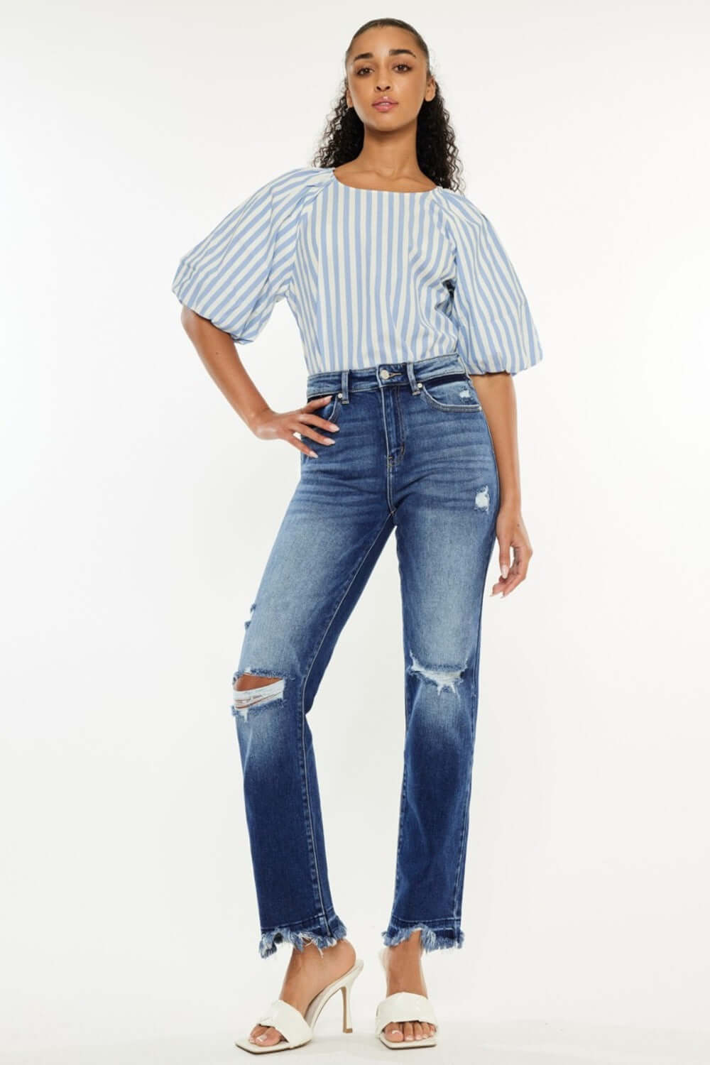 Woman wearing Kancan High Rise Distressed Slim Straight Jeans with a striped top and heels, showcasing stylish and versatile fashion.