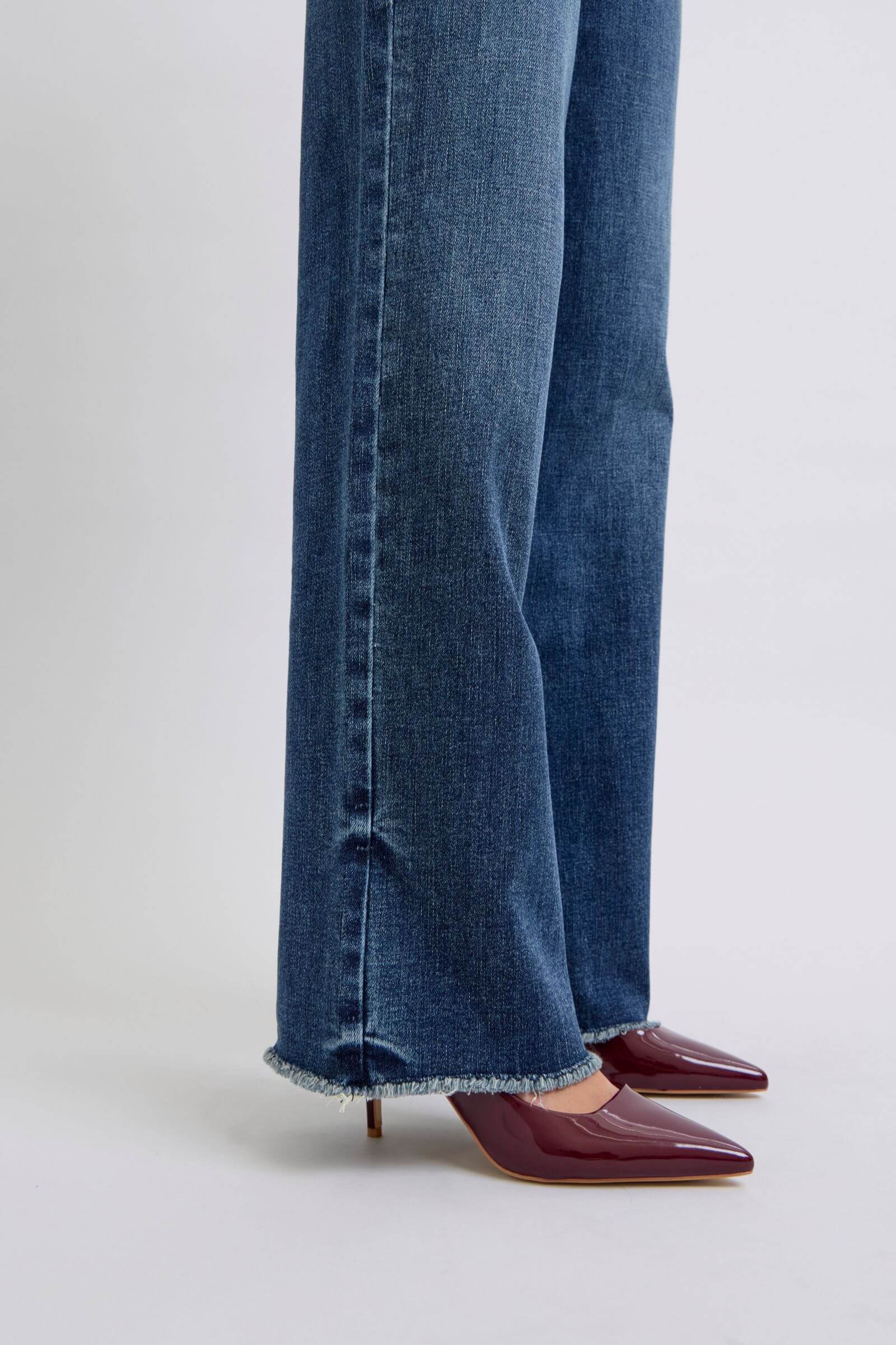 Stylish raw hem mid-rise jeans paired with sleek burgundy heels for a chic, edgy look.