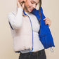 Model showcasing Love Tree zip-up cropped contrast reversible vest, smiling while holding the reversible side in blue.