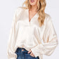 Woman wearing viscose notched long sleeve blouse with split neckline and relaxed fit, paired with blue jeans.