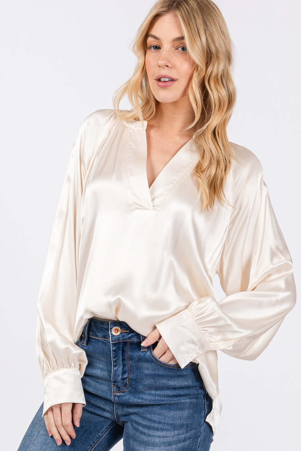 Woman wearing viscose notched long sleeve blouse with split neckline and relaxed fit, paired with blue jeans.