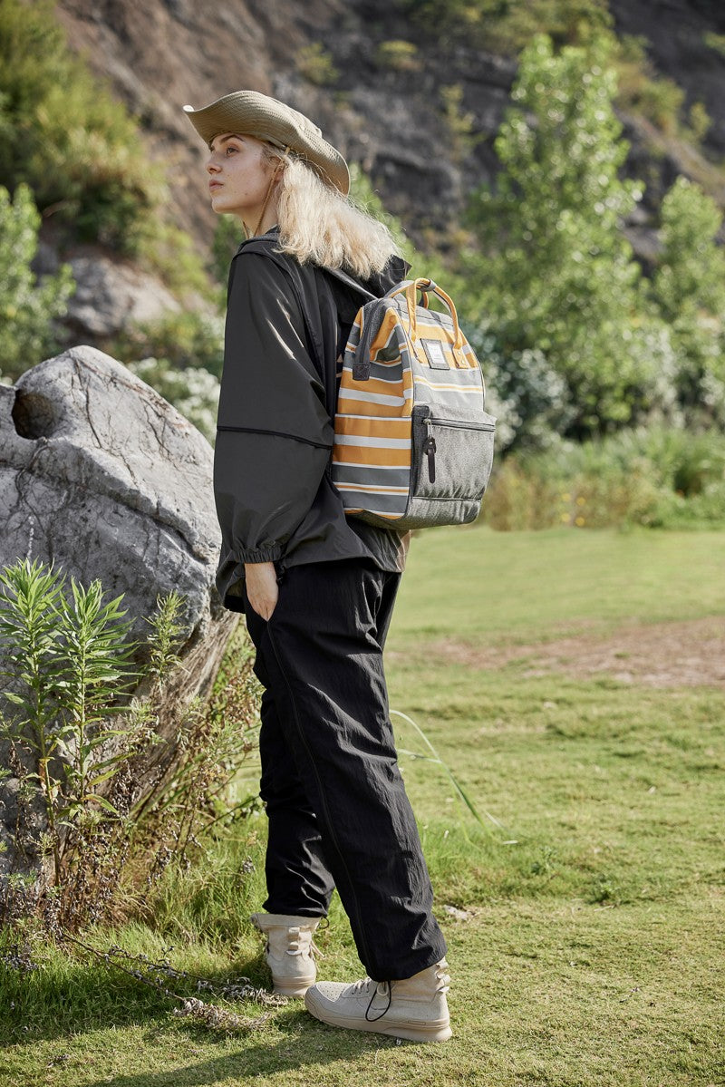 Person wearing a Himawari striped waterproof nylon backpack with side pockets, ideal for outdoor adventures.