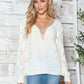 Woman wearing a cozy Bella Road Openwork V-Neck Long Sleeve Sweater in white, perfect for a stylish and warm look.