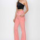 Model wearing high-rise side slit pink cargo bootcut jeans by Risen Jeans, styled with a black glittery one-shoulder top and heels