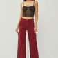 Woman wearing RISEN high rise wide leg cargo jeans in deep red, paired with a black top and heels. Trendy and stylish casual outfit.