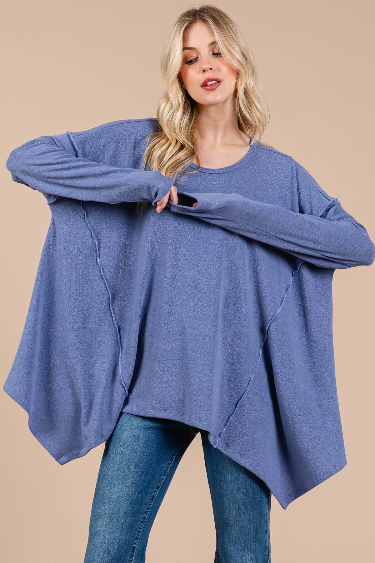 Woman wearing Ces Femme asymmetrical long sleeve top in blue with relaxed fit and hi-low hem for effortless, casual style.