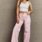 Woman wearing Raelene High Waist Wide Leg Jeans in Light Pink by Risen Jeans, styled with a white crop top for a chic and modern look.