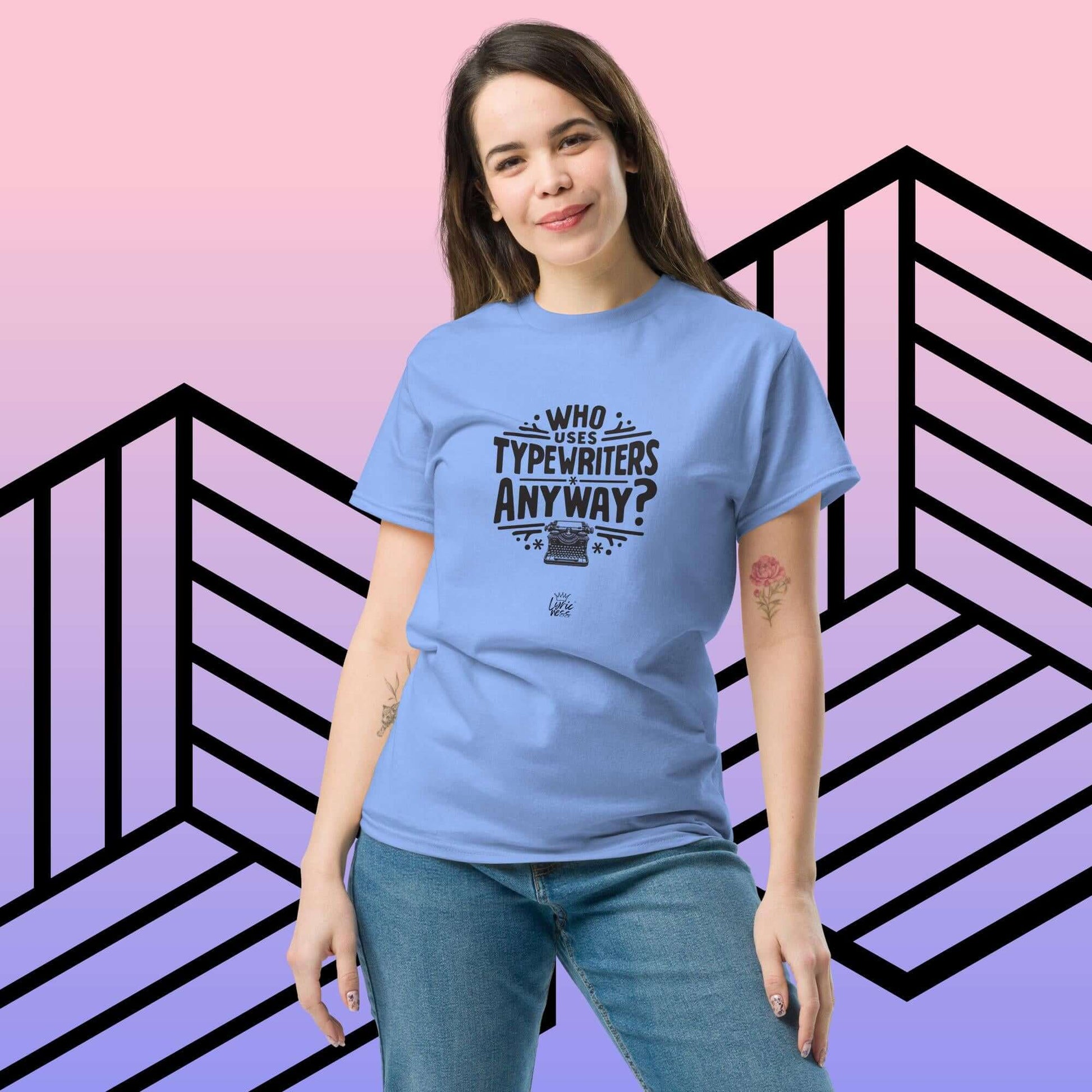 Person wearing blue "Who Uses Typewriters Anyway?" short-sleeve unisex t-shirt against geometric background